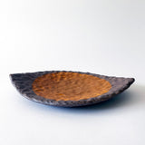 Handmade ceramic dish with a textured surface and a marigold sun on a white background