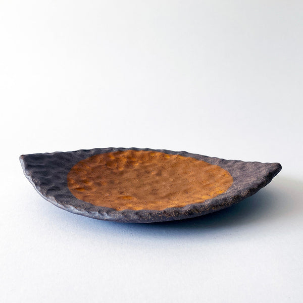 Handmade ceramic dish with a textured surface and a marigold sun on a white background